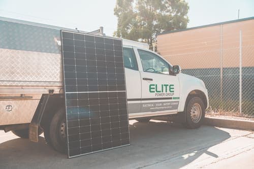 Solar panel leaning against utility truck promoting clean energy installation.